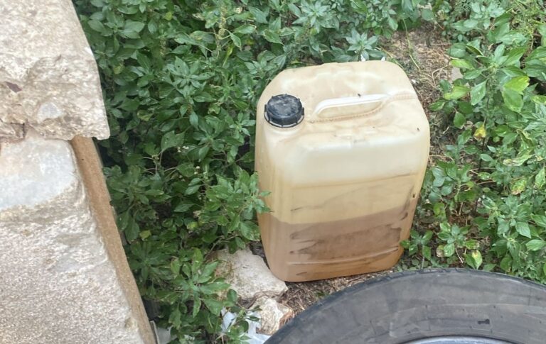 a plastic jug with brown liquid in the grass