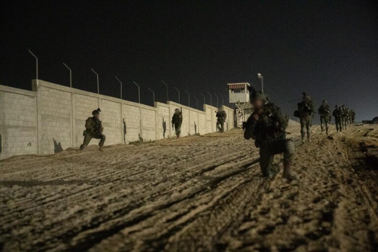 a group of people in uniform running on dirt near a wall