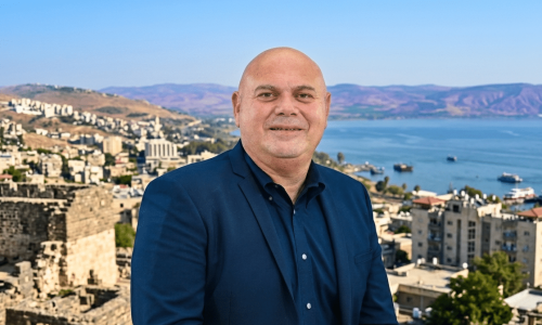 יוסי נבעה על רקע העיר טבריה. צילום: דוברות. עיבוד: AI