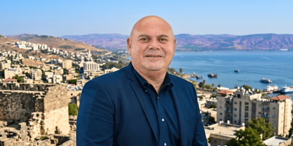 יוסי נבעה על רקע העיר טבריה. צילום: דוברות. עיבוד: AI